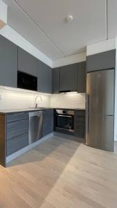 a kitchen with gray cabinets and stainless steel appliances at Modern family apartment next to metro easy access to Helsinki in Espoo