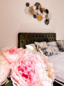 zwei rosa Blumen auf einem Tisch neben einem Bett in der Unterkunft Apartments Đurašević in Sveti Stefan