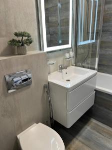 ein Badezimmer mit einem weißen Waschbecken und einem WC in der Unterkunft DeMar Apart Doroshenka in Lwiw