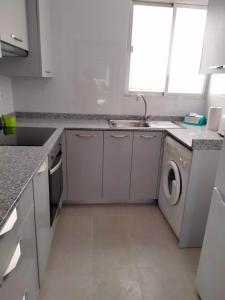 uma cozinha branca com um lavatório e uma máquina de lavar louça em Margaritas em Alcossebre