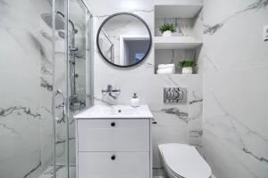 ein weißes Badezimmer mit einem Waschbecken und einem Spiegel in der Unterkunft Corolla Apartments Solidarności 96 in Warschau