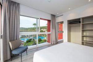 a bedroom with a large bed and a large window at HG Jardín de Menorca in Son Bou