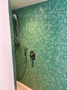 een groene betegelde badkamer met een douche met een slang bij House Botanique in Meise