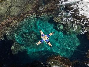 a man laying in the water next to the ocean at Green Island Coastal Homestay in Green Island