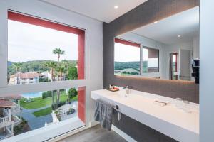 a bathroom with a large window and a white sink at HG Jardín de Menorca in Son Bou