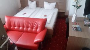 a red chair and a bed in a room at Gasthof Falter in Straubing