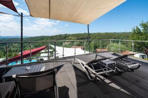 einen Balkon mit Stühlen und einem Tisch auf dem Dach in der Unterkunft Domaine de Chalvêches Hôtel SPA 4* in Faugères in Rhone-Alpes