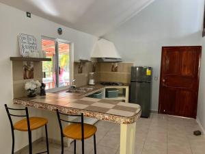 une cuisine avec un comptoir et deux tabourets sur un îlot de cuisine dans l'établissement Casa Villa Grand palapa frente al mar, à El Cristo