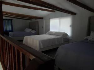 a bedroom with two beds and a balcony at Casa Villa Grand palapa frente al mar in El Cristo