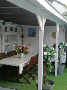 een tafel en stoelen onder een witte pergola bij maison calme avec piscine palmiers 300m de la plage pornichet centre in Pornichet