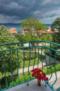 un jarrón de flores rojas sentado en un balcón en Family Hotel Orfei, en Nesebar