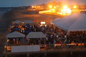 a large group of people standing under tents on the beach at Sandy Toes in Salisbury