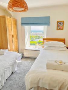 - 2 lits dans une chambre avec fenêtre dans l'établissement Gordy Hall -Sea facing Welsh cottage with stunning views, à Pendine