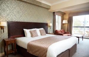 セットフォードにあるBell by Greene King Innsの大きなベッドと椅子が備わるホテルルームです。