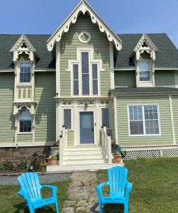 duas cadeiras azuis em frente a uma casa em Seabank House Bed and Breakfast Aloha em Pictou