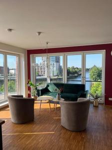 een woonkamer met stoelen en een tafel en ramen bij Penthouse-Wohnung mit Flussblick in Oldenburg