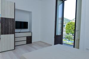 Schlafzimmer mit einem Bett, einem TV und einem Fenster in der Unterkunft L'Aurora Azzurra -Luxury Suites in Piano di Sorrento