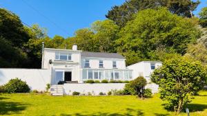 Gordy Hall -Sea facing Welsh cottage with stunning views في بينداين: منزل أبيض مع حديقة خضراء
