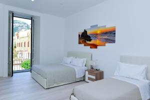 2 Betten in einem weißen Zimmer mit Fenster in der Unterkunft L'Aurora Azzurra -Luxury Suites in Piano di Sorrento