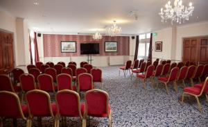 d'une salle de conférence avec des chaises rouges et une télévision à écran plat. dans l'établissement Bell by Greene King Inns, à Thetford