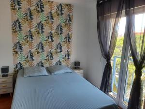 een slaapkamer met een blauw bed en een raam bij Coeur Marina climatisé terrasse parking in Fréjus