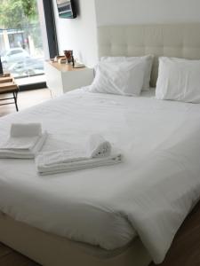 Una cama con sábanas blancas y toallas. en Up iConik, en Aveiro