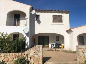 a large white house with a stone wall at Casa Vacanza Budoni Mare in Budoni