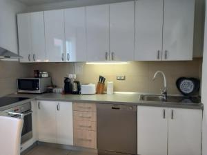 a kitchen with white cabinets and a sink at Apartman Zara in Zadar