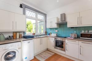 a kitchen with white cabinets and a washer and dryer at Lovely 3bed House-Private parking in Edinburgh