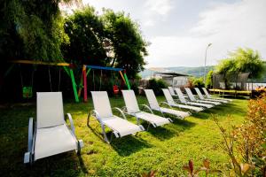 una fila de sillas blancas en un patio con parque infantil en Pensiunea Danubia, en Eşelniţa