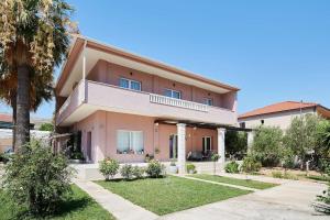 a large house with a palm tree in front of it at Apartman Babalui in Trogir