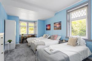 Lovely 3bed House-Private parking في إدنبرة: ثلاثة أسرة في غرفة مع جدران ونوافذ زرقاء