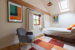a bedroom with a bed and a chair in it at The Cart Lodge at Grove Barn in Eye
