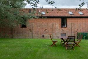 twee stoelen en een tafel in een tuin naast een bakstenen gebouw bij The Cart Lodge at Grove Barn in Eye