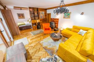 a living room with a yellow couch and an orange chair at Chalet Iris with sauna in Kolašin