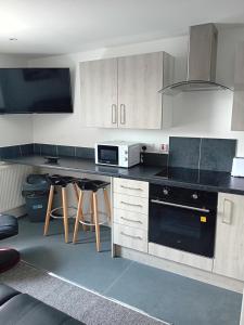 cocina con armarios blancos y encimera negra en Windies apartment 3, en Bridlington