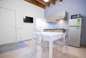 a kitchen with a white table and chairs and a refrigerator at Case Ruggieri Apartments - Don Leonardo in Gratteri