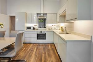 a white kitchen with wooden floors and white cabinets at Host & Stay - Brooklands Timeless in Scarborough +12 photos