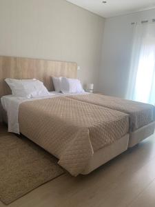 1 dormitorio con 1 cama grande con sábanas y almohadas blancas en Apartamento Fátima Sanctuary, en Fátima