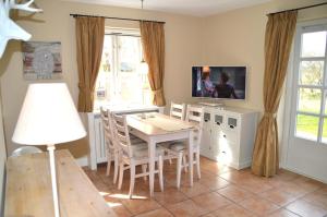 a dining room with a table and chairs and a tv at Deichhof Whg 6 in Dunsum