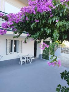 a table and chairs under a tree with purple flowers at Apartment Filip in Trogir