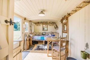 Caravana con dormitorio, mesa y cama en Littlestock Shepherds Hut en Shipton under Wychwood