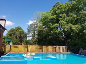 una piscina azul con una valla de madera y árboles en BELLA CASA EN VILLA LIBERTAD en Leandro N. Alem