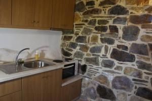 una cucina con parete in pietra e lavandino di Rosales stone house ad AmigdhalokeFálion