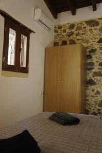 um quarto com uma cama e um armário de madeira em Rosales stone house em AmigdhalokeFálion