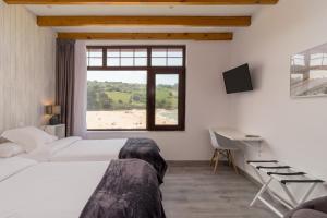 a bedroom with two beds and a desk and a window at Hotel SanMar in Cóbreces