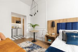 a bedroom with a bed with a blue headboard and a table at Movo II Old Town Apartments in Warsaw