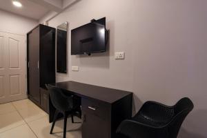 Zimmer mit einem Schreibtisch und einem TV an der Wand in der Unterkunft IVY RESIDENCY in Thiruvananthapuram