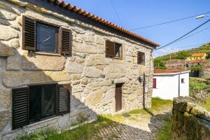 an old stone building with shutters on it at Isatour Casa na Serra in Adsamo