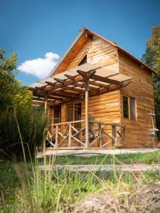 a log cabin with a porch and a deck at Charming cabin surrounded by nature in El Escudero